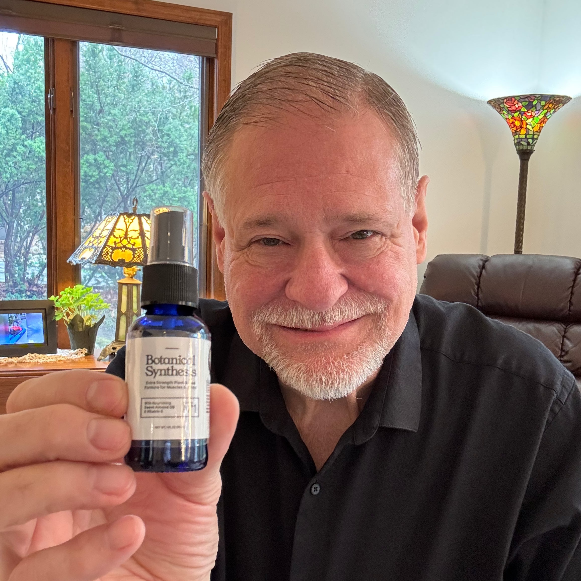 Man holding a bottle of Botanical Synthesis